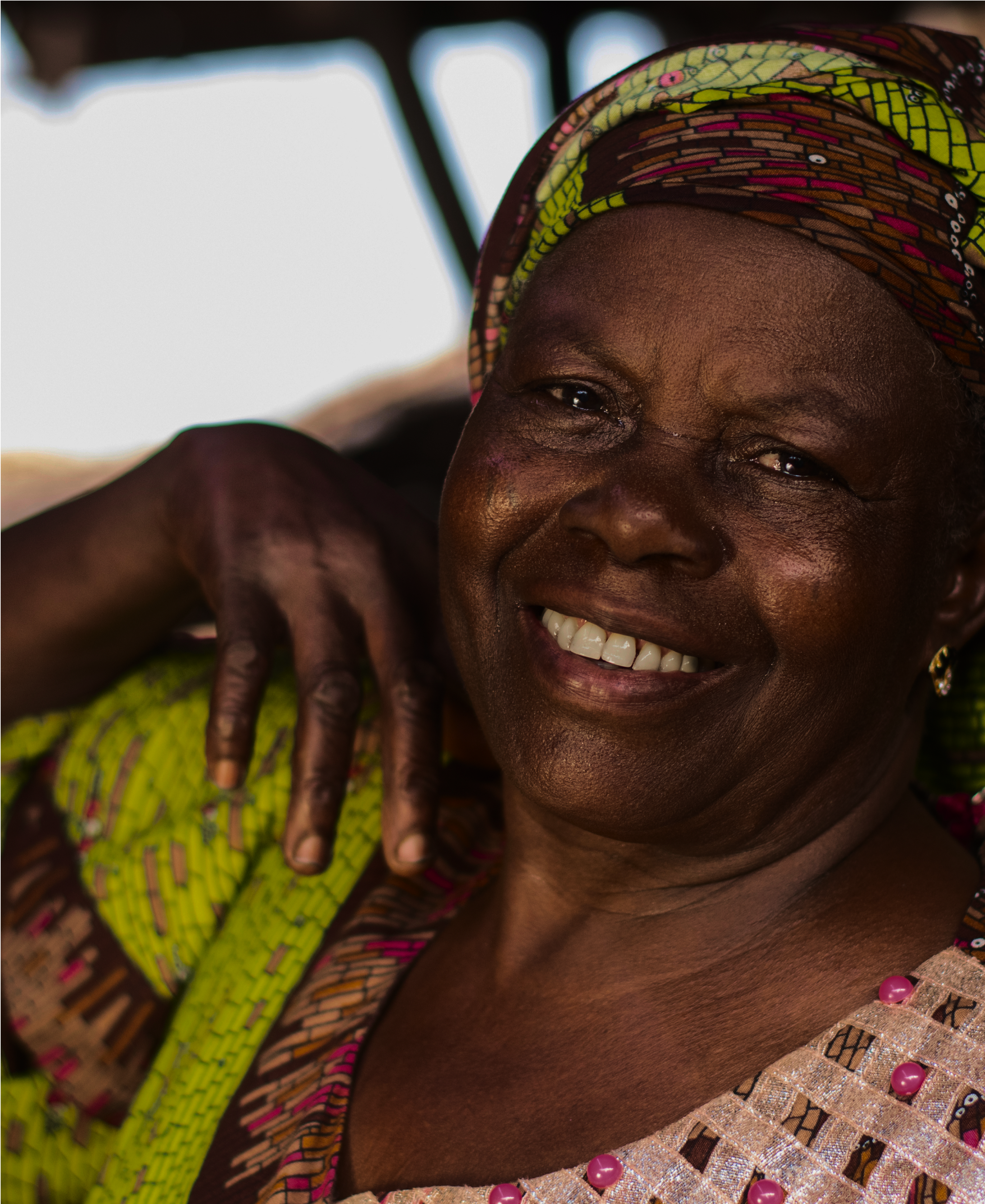 An elderly woman smiling in a colourful head wrap